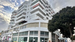 A multi-story building with a modern architectural design, featuring balconies and large windows.
