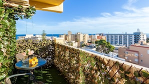 Un balcón con mesa y sillas, con vistas a la ciudad y al mar.