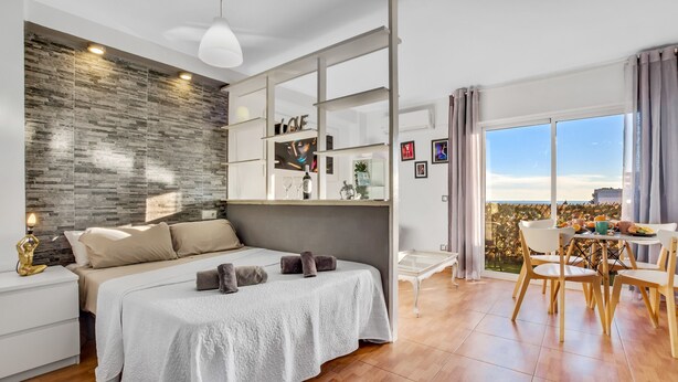 Un dormitorio moderno con una cama grande, un cabecero de madera, una zona de comedor con vistas y un balcón.