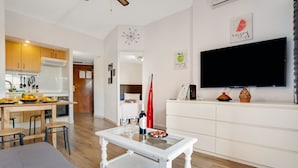 A modern living room with a white sofa, a glass-top coffee table, and a flat-screen TV mounted on the wall. - Solpor de Steram Flats Benalmadena (Benalmádena)