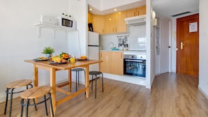 A compact kitchen with wooden cabinets, a microwave, and a dining area with stools. - Solpor de Steram Flats Benalmadena (Benalmádena)