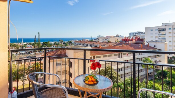 A balcony with a table, chairs, and a view of the sea and buildings. - Solpor de Steram Flats Benalmadena (Benalmádena)