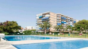A swimming pool area with a multi-story building in the background. - Solpor de Steram Flats Benalmadena (Benalmádena)