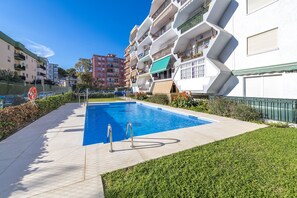 A swimming pool with a geometric poolside design, surrounded by a well-maintained lawn and a fence. - Noasti de Steram Flats Torremolinos (Torremolinos)
