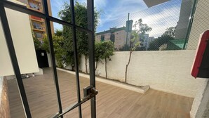 A view through a metal gate into a courtyard with wooden flooring, a white wall, and a tree. - Noasti de Steram Flats Torremolinos (Torremolinos)