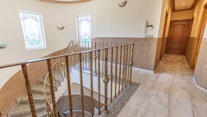A grand staircase with ornate railings and a marble floor, leading to a landing with a wooden door. - Real Dream Villa by Fidalsa (Jacarilla)