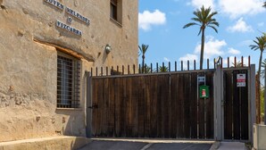 A building with a sign reading "Joven Melendez o Vizcarraga" and a wooden gate with a green trash bin and a red emergency alarm sign. - Historical Palms Villa by Fidalsa (Elche)