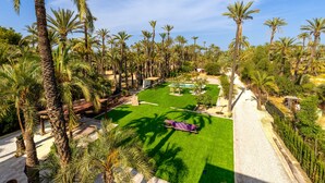 A well-maintained garden with palm trees, a swimming pool, and a patio area. - Historical Palms Villa by Fidalsa (Elche)