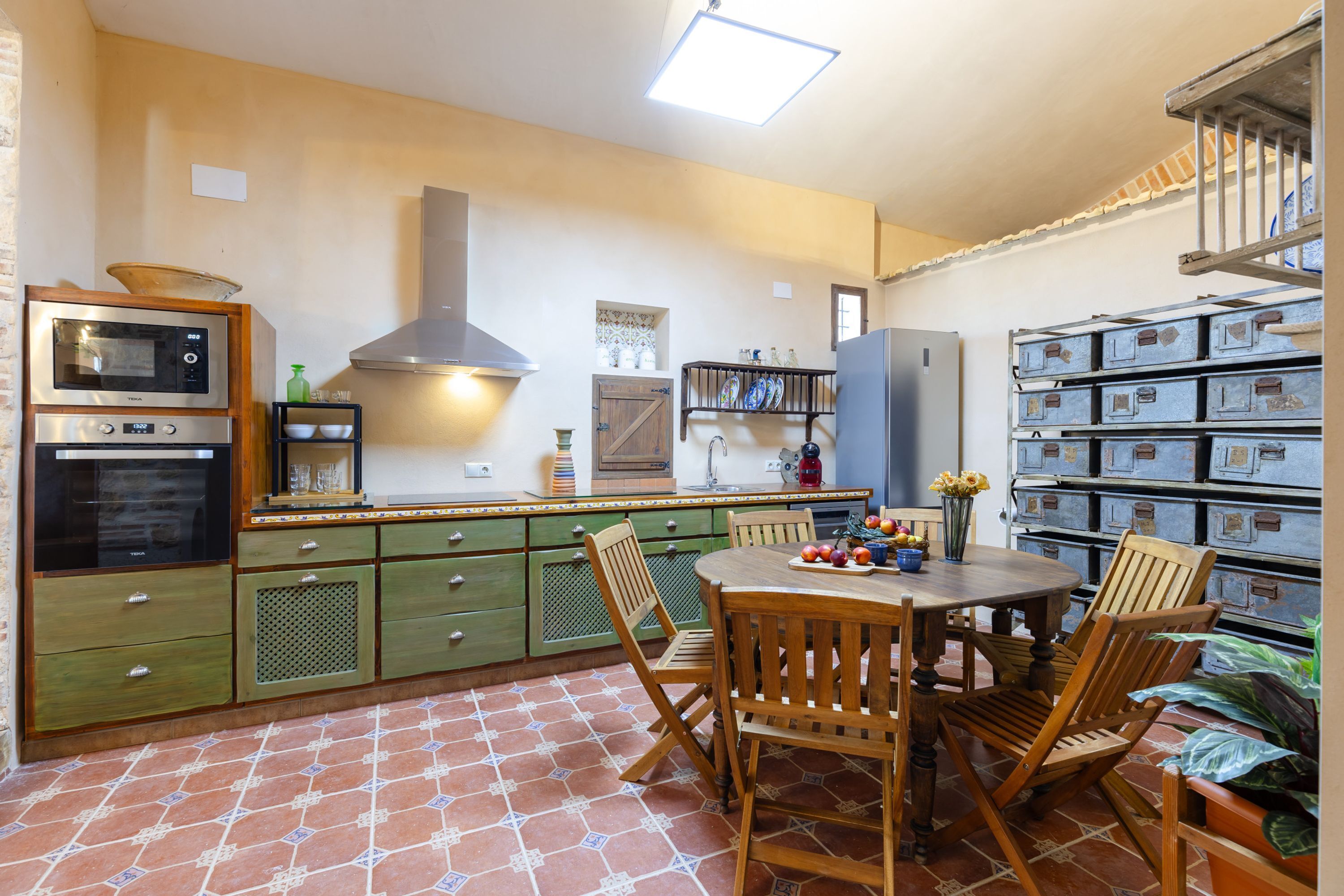 Una cocina con armarios verdes, una mesa de madera y sillas.