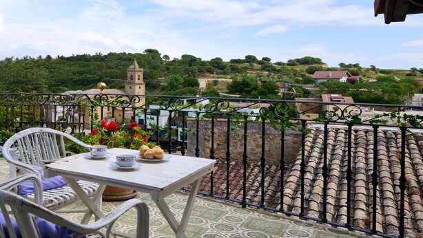 A balcony with a table set for two, overlooking a village with a church tower and greenery. - Wine Escape by Fidalsa (Villabuena de Alava)