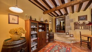 A rustic interior with exposed wooden beams, a wooden cabinet with dishes, a patterned rug, and a wooden chair. - Wine Escape by Fidalsa (Villabuena de Alava)