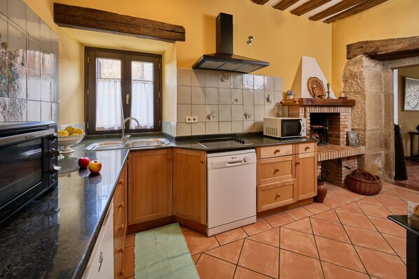 A kitchen with wooden cabinets, a dishwasher, a microwave, and a brick oven.