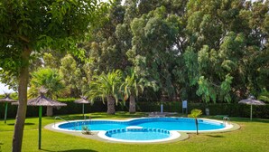 A swimming pool surrounded by grass and trees, with a circular deck and a palm tree nearby. - Coral Seashell Ground Floor by Fidalsa (Guardamar del Segura)