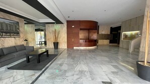 A modern lobby with a marble floor, a sofa, a coffee table, and a reception desk.
