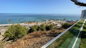 A coastal view with a road leading to a beach, palm trees, and a casino building in the background.