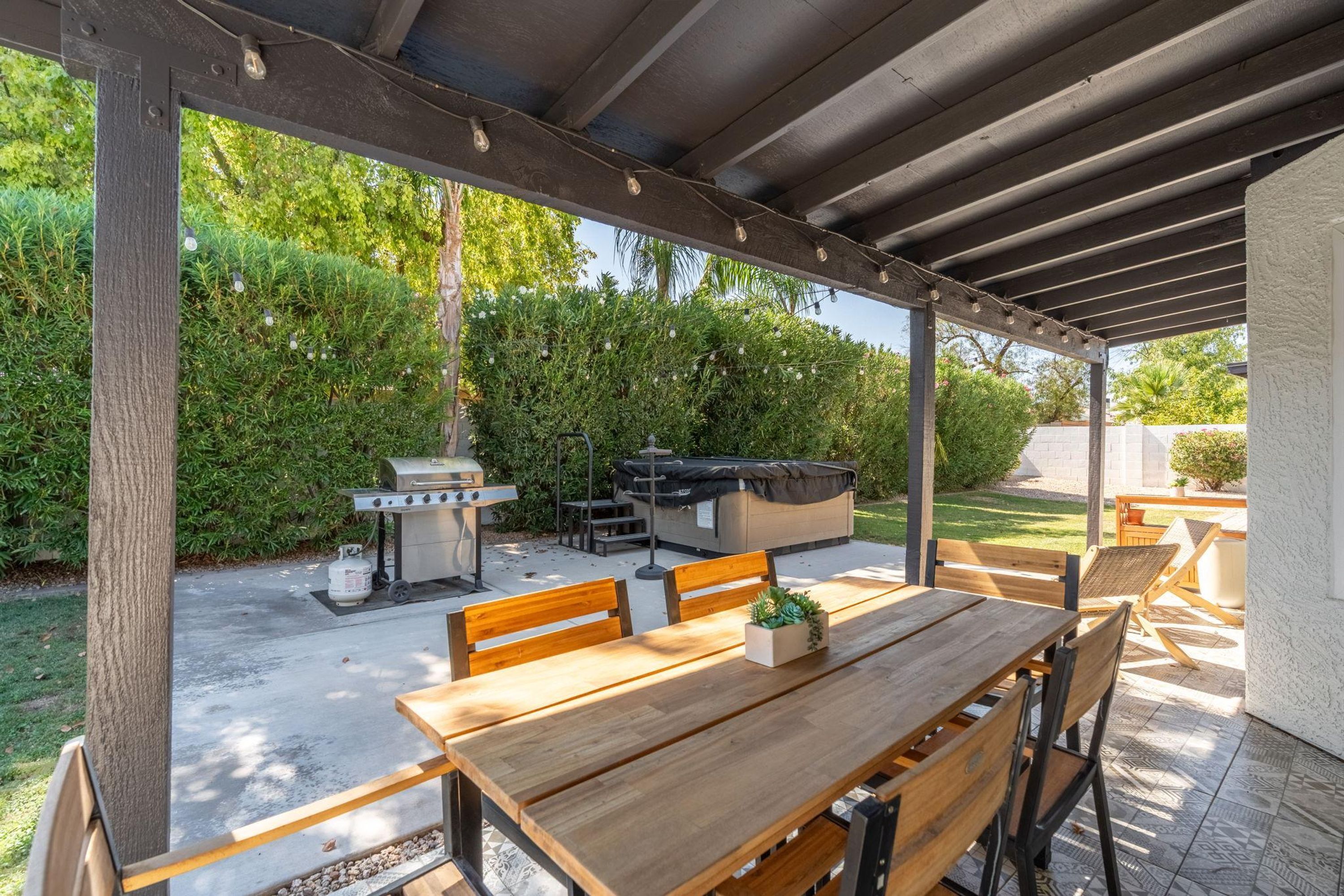 Eine Terrasse im Freien mit Holztisch und -stühlen, einem Grill und einer Grillgelegenheit.