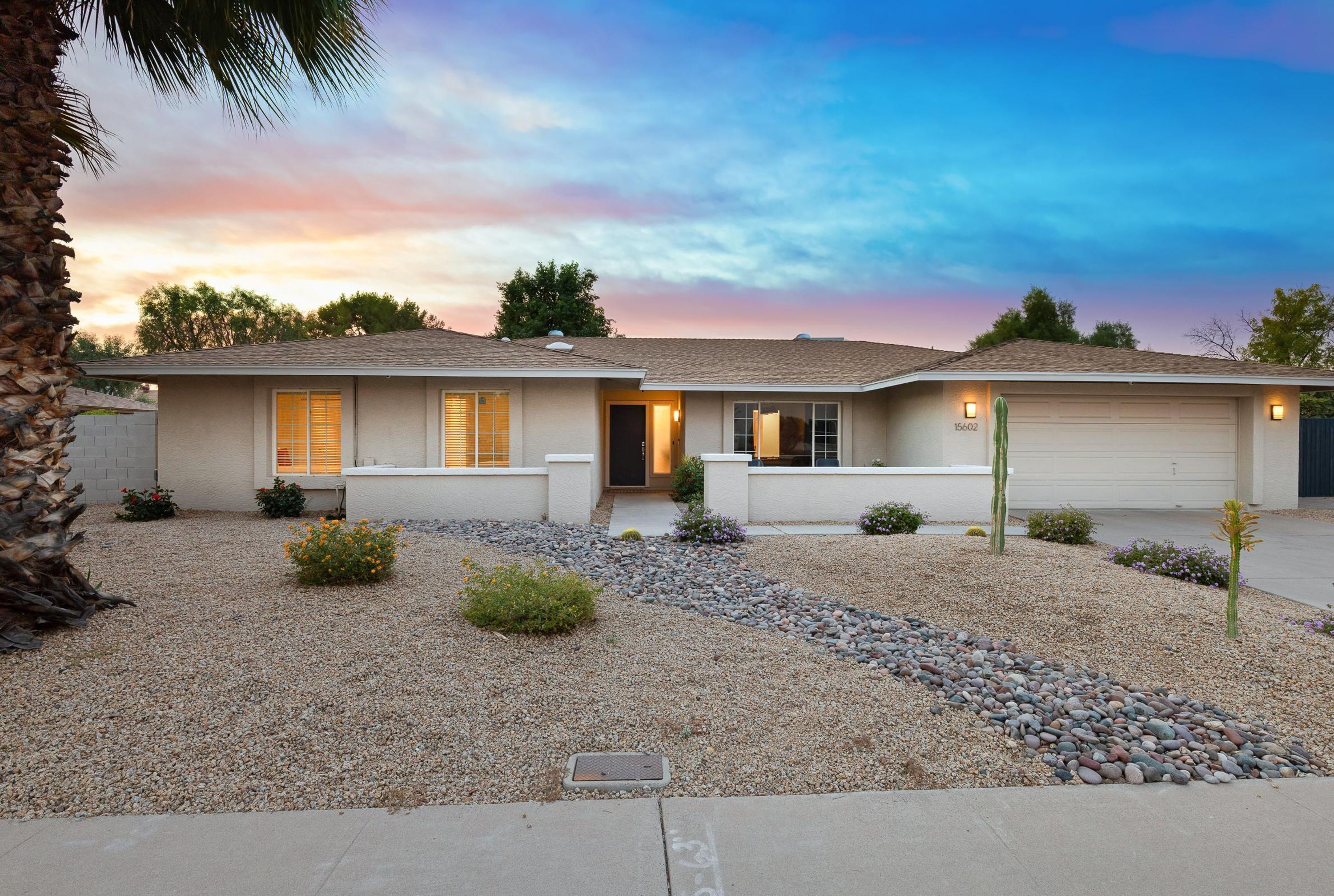 A two-story house with a front entrance, a garage, and a well-maintained garden with gravel pathways and small plants.