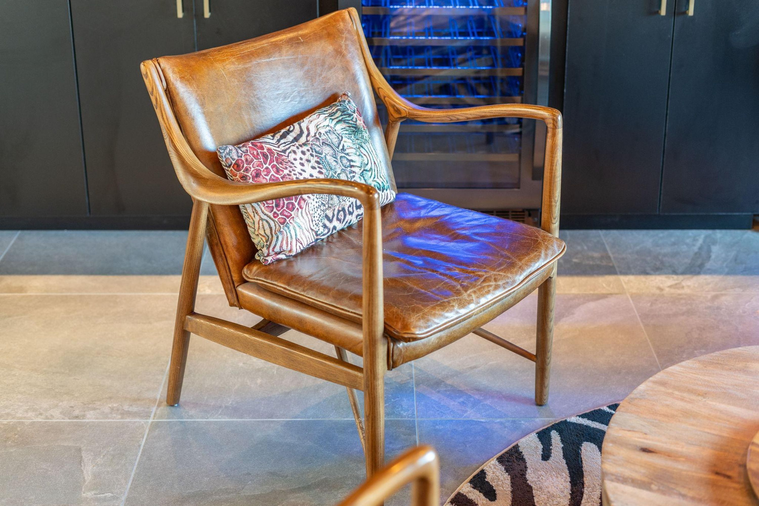 A wooden chair with a leather seat and a patterned cushion.