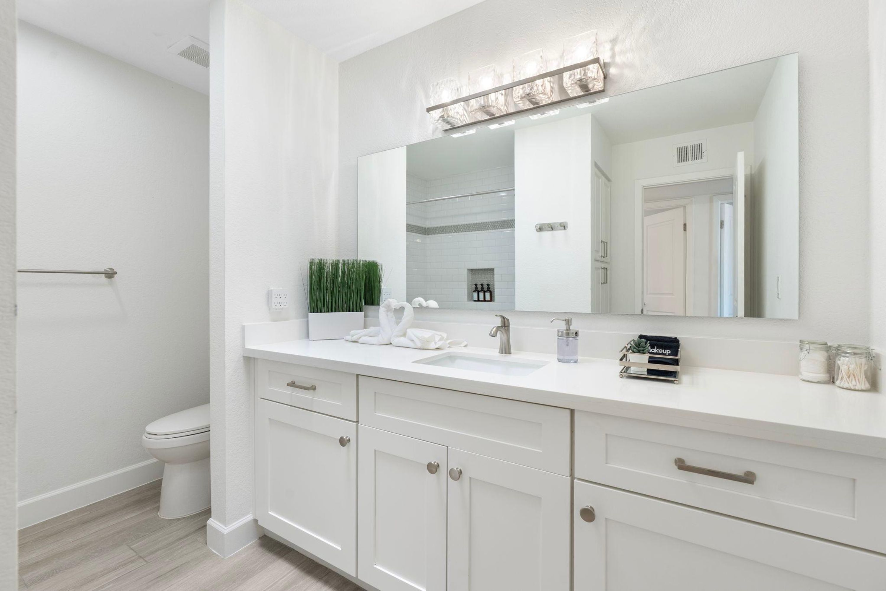A modern bathroom with a white vanity, a large mirror, and a shower area.