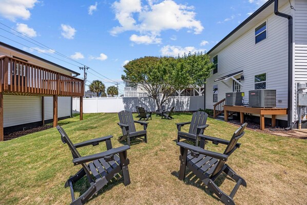 A backyard with a covered patio area, outdoor seating, and a tree providing shade.
