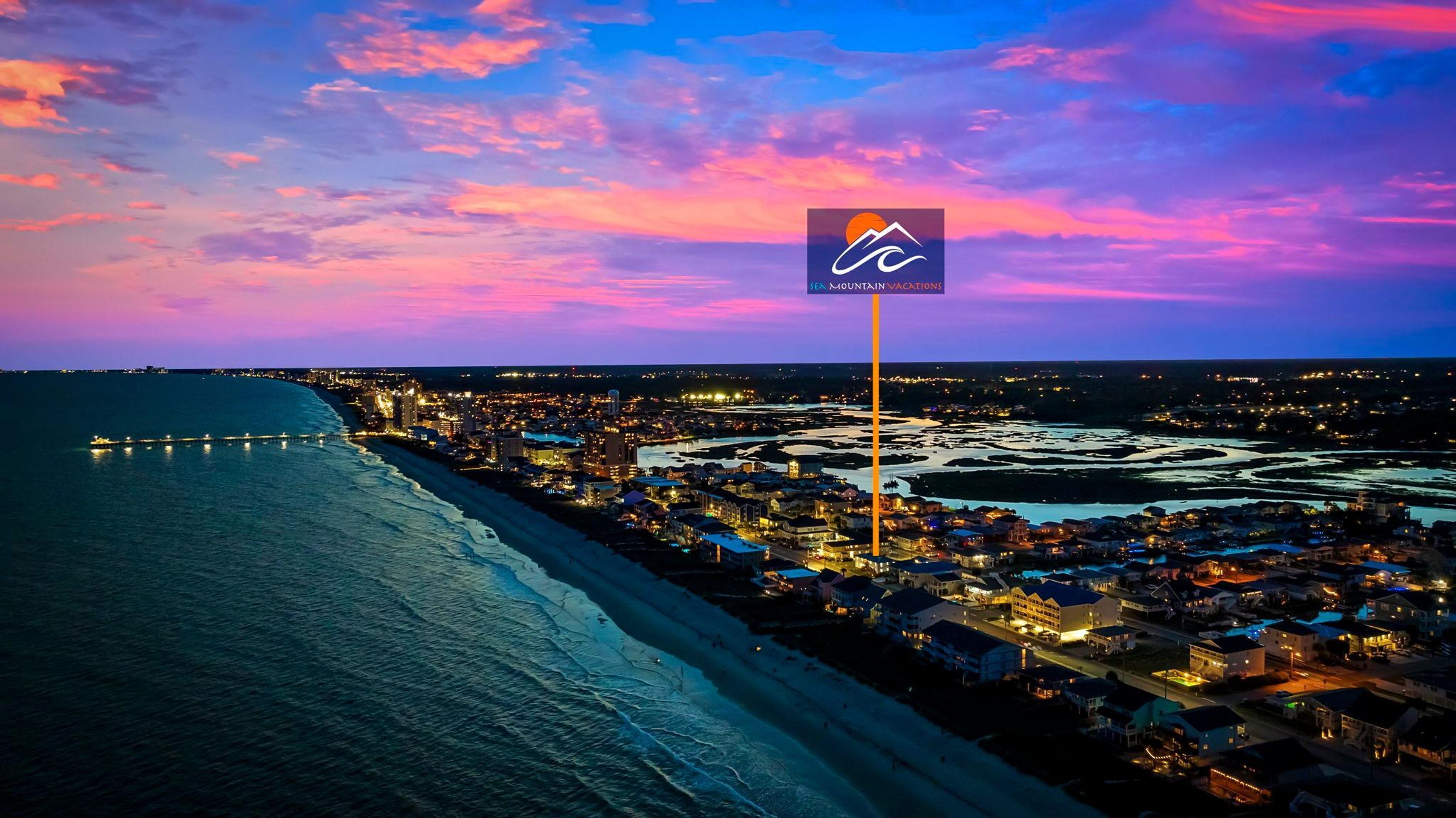 Une ville côtière au crépuscule, avec une enseigne d’hôtel bien visible indiquant qu’il offre une vue sur la plage.