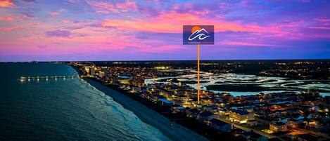 A coastal town at dusk with a prominent hotel sign indicating a beach view.