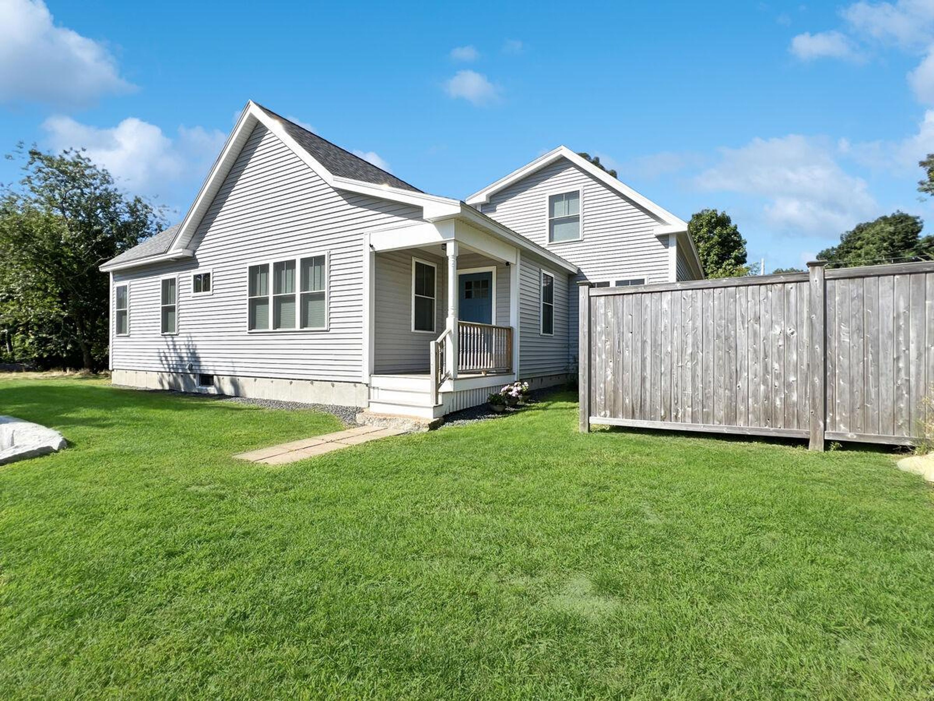 A two-story house with a front porch and a wooden fence.