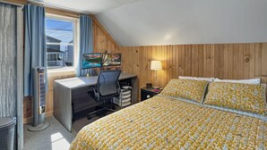 Un dormitorio con cama, escritorio, silla y ventana con cortinas.