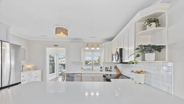 A modern kitchen with white cabinetry, a large island, and a view to the outside. - Magnolia House in North Myrtle Beach (North Myrtle Beach)