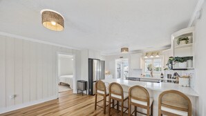 A modern kitchen with a central island, wooden chairs, and a built-in refrigerator. - Magnolia House in North Myrtle Beach (North Myrtle Beach)