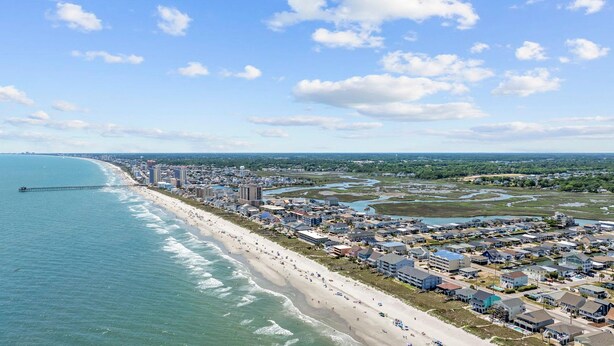 A coastal cityscape with a long sandy beach, a pier extending into the ocean, and a mix of residential and commercial buildings. - Surf Sun Pura Vida - 3 (North Myrtle Beach)