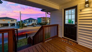 A porch with a wooden railing, a black door, and a mailbox. - Surf Sun Pura Vida - 3 (North Myrtle Beach)