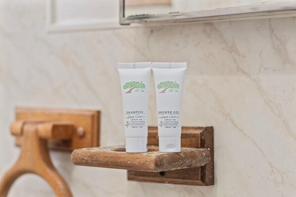 Deux tubes blancs de shampoing et de gel douche, ornés d’un logo représentant un arbre, sont posés sur une étagère en bois.