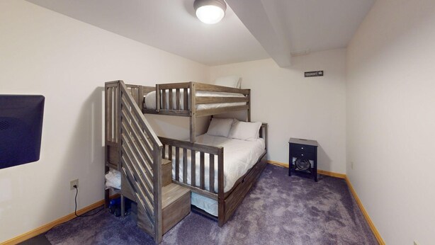 A bunk bed room with a small desk and a fan. - Beechwood Home in Mendon (Rutland)