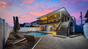 A two-story house with a swimming pool, outdoor seating, and a staircase leading to the upper level. - Summer Breeze in North Myrtle Beach (North Myrtle Beach)