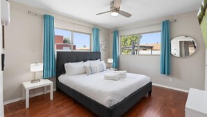A bedroom with a bed, a nightstand, a ceiling fan, a window with curtains, and a mirror. - Edgemont in Scottsdale (Scottsdale)