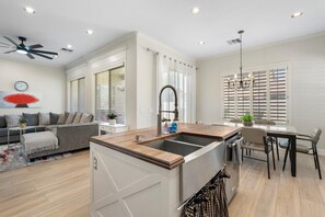 A modern kitchen with a central island, a dining area with a table and chairs, and a living room with a sofa and a coffee table. - Dublin in Gilbert With 4 Bedrooms and 2 Bathrooms (Gilbert)
