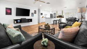 A modern living room with a black leather sofa, a coffee table, and a flat-screen TV mounted on the wall. - Devonshire in Scottsdale (Scottsdale)