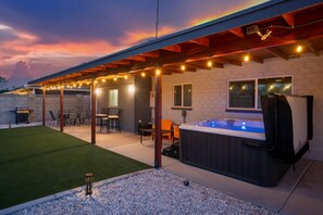 An outdoor patio with a hot tub, string lights, and a covered seating area. - Devonshire in Scottsdale (Scottsdale)