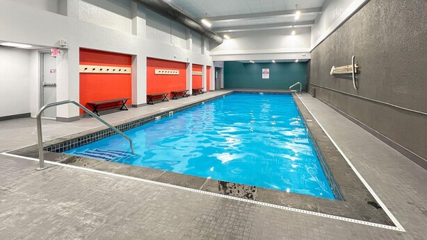 An indoor swimming pool with a clear blue water, surrounded by walls with red and grey panels, and a ceiling with recessed lighting. - Mt Green 3-f04 in Killington (Killington)
