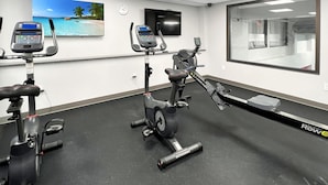 A gym with stationary bikes, a treadmill, and a rowing machine. There is a clock on the wall and a TV mounted above the equipment. - Mt Green 3-f04 in Killington (Killington)