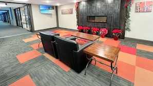 A conference room with a long table, black chairs, and a fireplace with red flowers. - Mt Green 3-f04 in Killington (Killington)