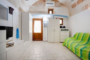 Un dormitorio con cama, armario, televisor y una puerta que da a otra habitación.