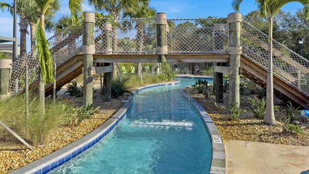 A pool with a water slide, surrounded by palm trees and a wooden bridge. - PLW4277 Summary:<br>Stor (Kissimmee)