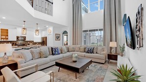 A spacious living room with a large sectional sofa, a coffee table, and a dining area with a kitchen in the background. - PLW4277 Summary:<br>Stor (Kissimmee)