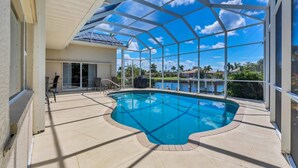 An indoor swimming pool with a glass ceiling, surrounded by lounge chairs and a view of a lake and palm trees. - BVC265 Summary:<br>Punta (Punta Gorda)