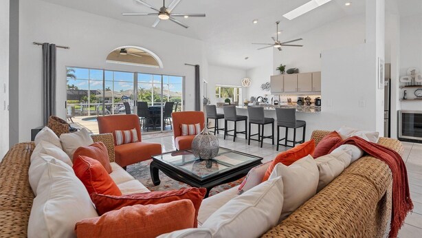 A spacious living room with a large sofa, a coffee table, and a dining area with chairs and a kitchen in the background. - BVC265 Summary:<br>Punta (Punta Gorda)