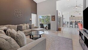 A spacious living room with a modern sofa, a glass coffee table, and a view of the outdoor patio. - BVC265 Summary:<br>Punta (Punta Gorda)