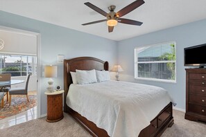 A bedroom with a bed, bedside lamps, a ceiling fan, a TV, a window with blinds, and a view of the outdoors. - BVC265 Summary:<br>Punta (Punta Gorda)
