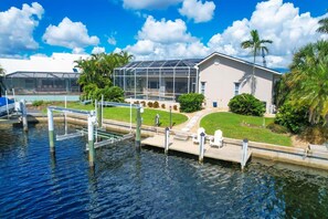 A waterfront property with a glass-enclosed structure, a dock, and well-maintained landscaping. - BVC265 Summary:<br>Punta (Punta Gorda)